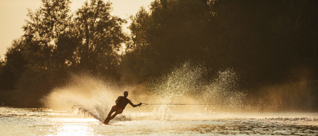 Man,Water,Skiing,At,Sunset.,Man,Riding,Wakeboard,On,Lake