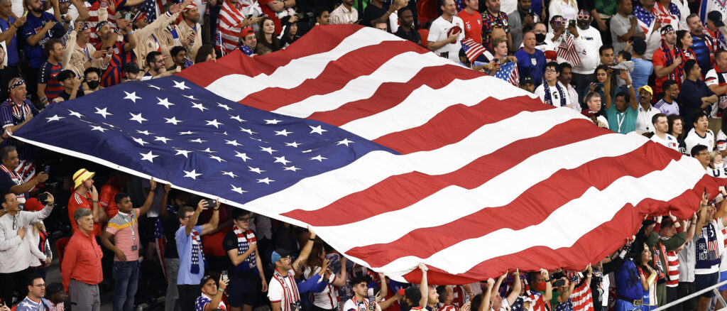 A USA flag waves during the FIFA World Cup Qatar 2022 Group B match between USA and Wales at Ahmad Bin Ali Stadium on November 21, 2022 in Doha, Qatar. (Photo by Tim Nwachukwu/Getty Images)