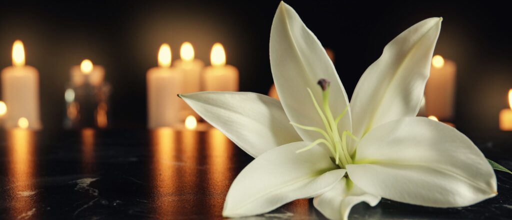 White,Lily,And,Blurred,Burning,Candles,On,Table,In,Darkness,