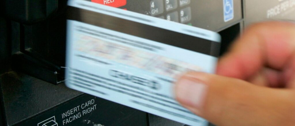 Customer swipes credit card at a gas pump at a Phillips 66 gas station in Centennial, Colorado