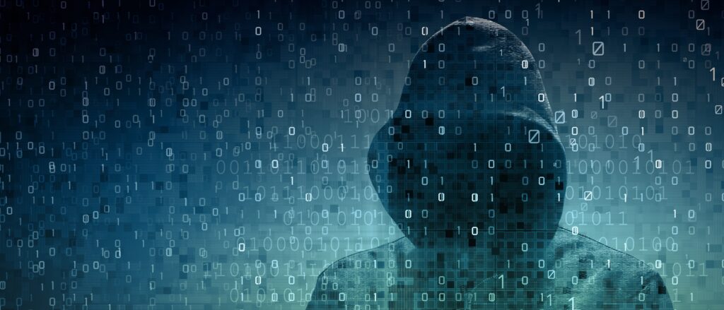Hooded man holds laptop computer as cyber code is projected on him in this illustration picture