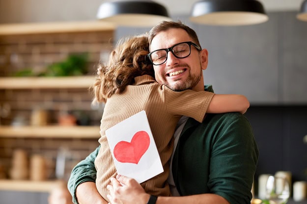 110 Best Happy Father’s Day Quotes, Sayings and Wishes to Show Your Love A happy Father hugging his child while holding a Father