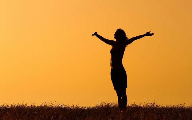 110 Short Quotes That Hit Hard About Motivation, Love and the Meaning of Life A woman at sunrise outside stretching her arms towards the sky.,