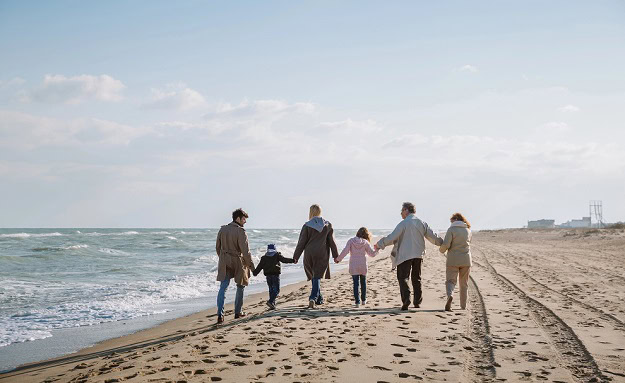 125 Family Quotes to Share the Love and Laughter and Strengthen Your Bonds A happy family walking on a beach.
