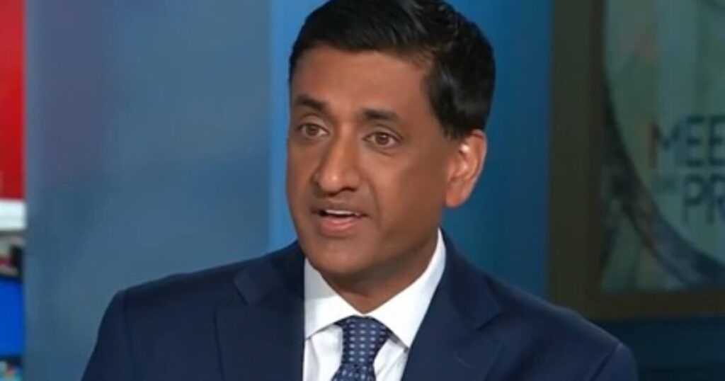 Man in a blue suit speaking during a television interview, focused on political topics and current events.
