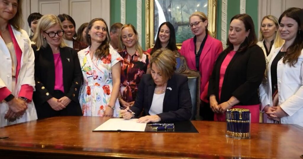 Massachusetts Governor Maura Healey signed the bill, surrounded by grinning, giggling females.