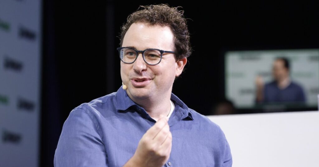 Speaker engaging with the audience at a tech conference, discussing innovative ideas with a microphone and visual presentation in the background.