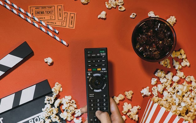The Most Hilarious Lines of All Time A tv remote, popcorn, a coca cola in a glass and movie tickets.